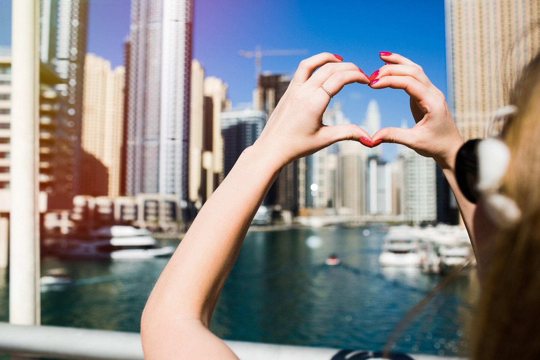 lady-with-red-nails-shows-heart-with-her-fingers-before-skyscrap